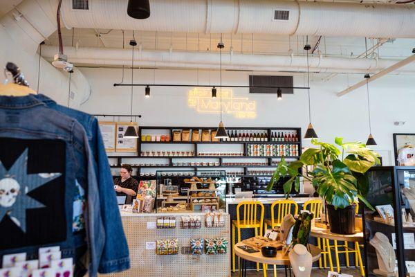 Photo of the scene when you entere the store including a bar with yellow chairs, a neon "Shop Made in Maryland" sign, and denim jackets.