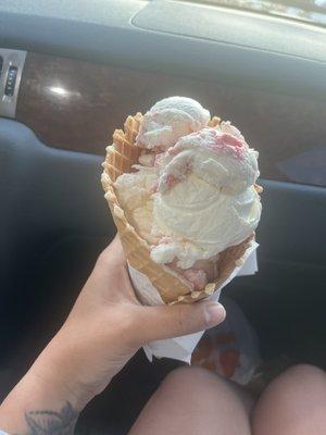 Small strawberry cheesecake ice cream in a waffle cone