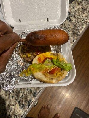 A burger tray with lettuce, ketchup,and lettuce( hence the lettuce) wilted.With a burnt a$$ corn dog.