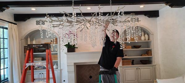 Alex hanging the glass "leaves" on this chandelier that looks like tree branches