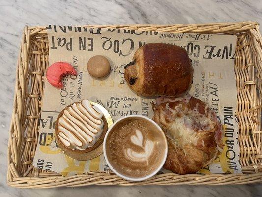 Strawberry and Coffee Macarons, Chocolate Croissant, lemon tart, ham and cheese Croissant, and a Cappuccino