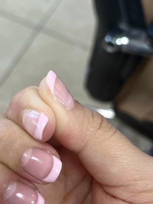 The gel is spilling over the cuticle, the pink doesn't cover the mail, and there's bubbles she tried to file off and left a hole.