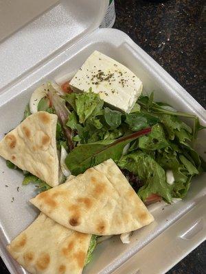 Side of Greek salad with pita and a block of feta cheese