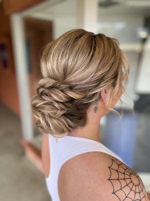 Romantic wedding updo hairstyle with a voluminous low bun, volume at the crown, and loose curls framing the face.