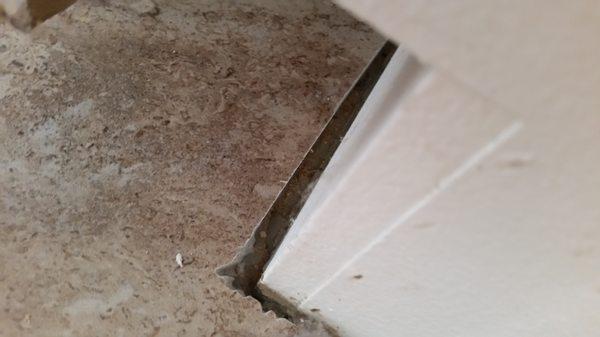 Edge of tile near stove no grout or caulk put in place, open gap left