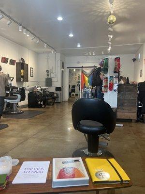 A view of the shop floor from the waiting bench. Various queer culture icons decorate the interior.