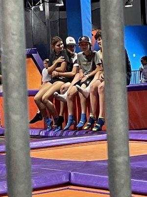 Kids sitting on the safety pads, one with his arms around a girl sitting on his lap!