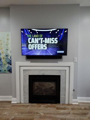 55 inch Tv mounted with soundbar above fireplace