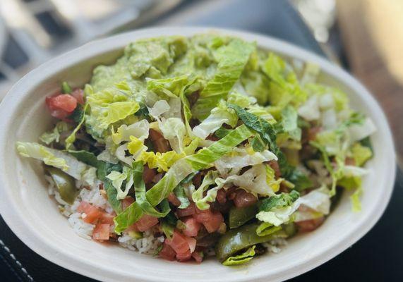 Bowl with white cilantro rice, grilled chicken, avocado, red salsa, green peppers, and pico de gayo.