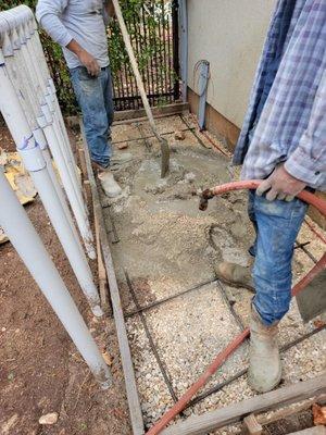 Workers adding cement to the hole and mixing in the hole - no bucket or wheel barrel