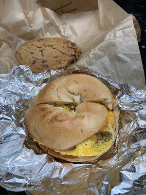 Sausage, egg, and cheese breakfast sandwich on a plain bagel. Chocolate chip cookie.