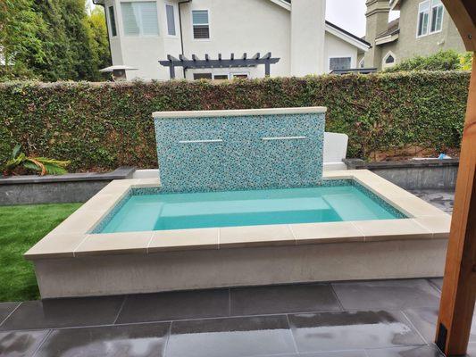 Outdoor spa with custom tiled waterfall wall.