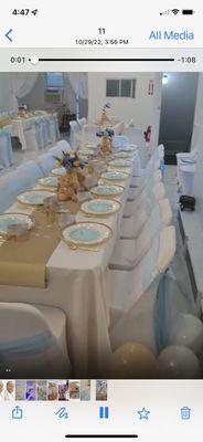 Baby blue tie backs with gold runner, floral centerpiece, and take home teddy bears.