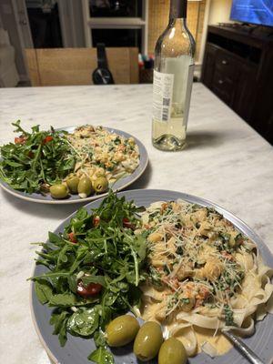 Bay scallops in a white wine sundried tomato cream sauce over fettuccine nests with a simple lemon garlic olive oil arugula salad