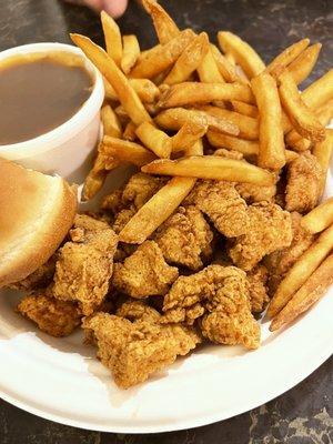 Chicken nuggets with mashed potatoes and gravy, and sweet roll.