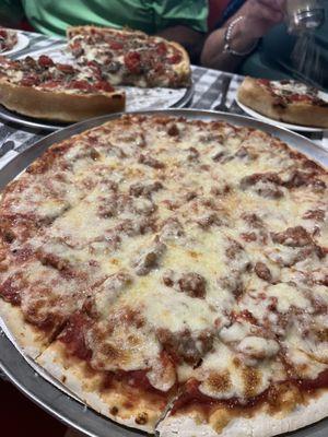 14" sausage pizza. Background is a Momma 's Teresa 's Pan Pizza with sausage, mushroom and tomato.