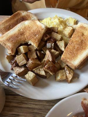 Scrambled eggs with home fries and toast.