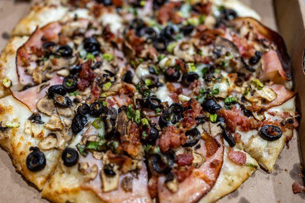 Sizzlin' Bacon Classic ($18) Crispy bacon, tender ham, sliced mushrooms, olives and green onions on creamy garlic sauce.