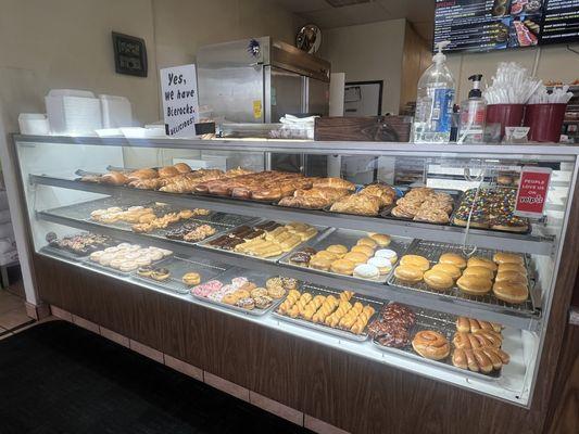 Donut display case with croissant and beer rocks on the top shelf