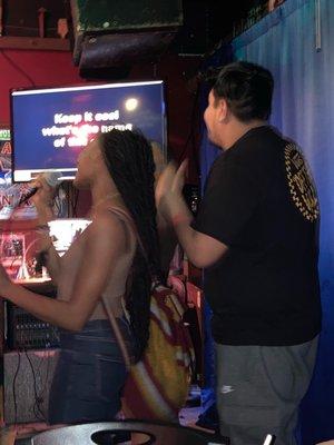 Karaoke joy even when under the yoke of an oppressive fascist playlist.  Who gets to sing? Not you Purpler