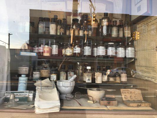 Front window display of vintage medicine bottles and Pharmacy preparation tools .