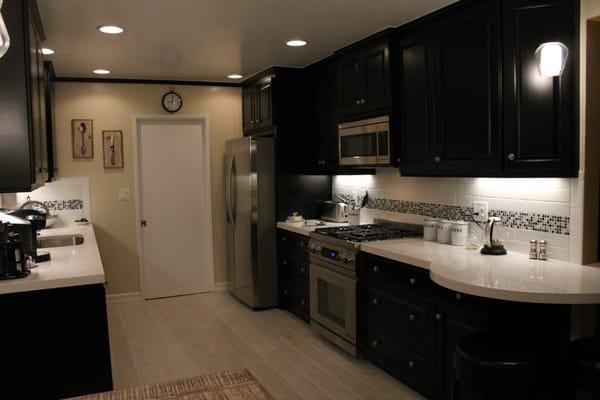 Black and white kitchen with solid maple cabinets stained black, nice grain shows through up close, and a round table island.