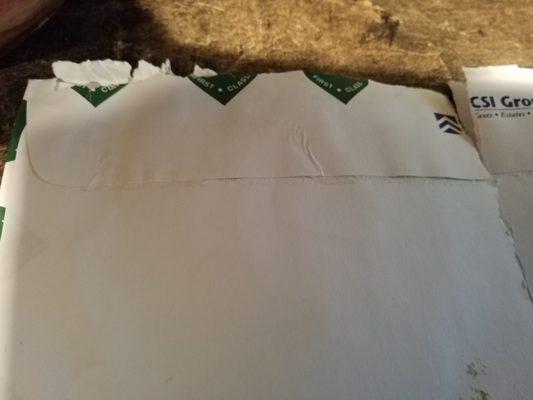 Envelope that was both resealed and ripped open by either a finger or letter opener.