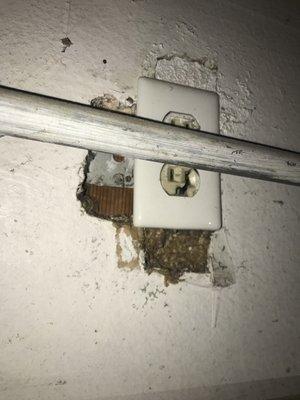 Water pipe goes right across broken electrical outlet bottom of that has rat dropping