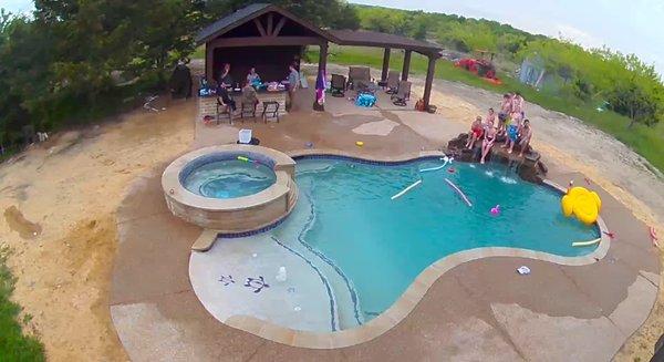 Pool with outdoor kitchen and pergola (before landscaping), with hot tub and grotto waterfall.