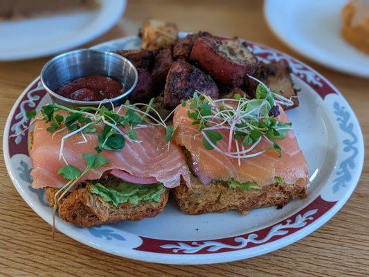 salmon lox and avocado with pickled onions on a biscuit with flavorful potatoes