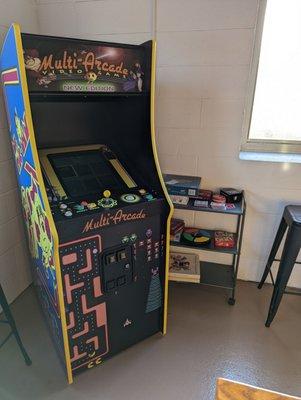 Arcade machine and game shelf nestled in the back corner. There's also a foosball table.