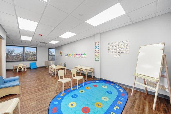 Classroom with brightly colored rug and whiteboard.