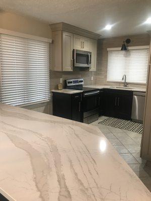 Cambria quartz countertops and painted black and taupe cabinets with gold hardware.