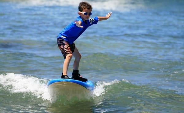 Camper Ben riding his surfboard all the way from the ocean to the shore.