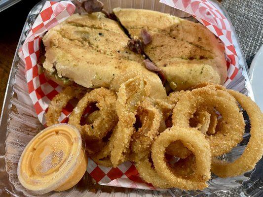 Tri tip sandwich with onion rings and bang bang sauce