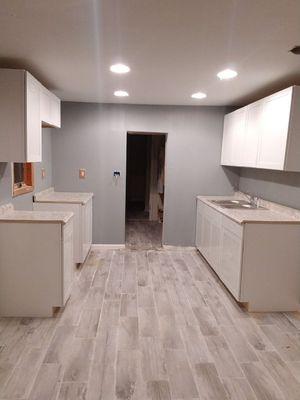 Kitchen cabinets installed, trim needs to be done, sink installed, room painted, floors tiled, recessed lights installed