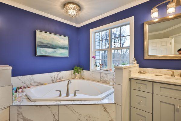 Master bathroom remodel with corner bathtub & marble lined tiles