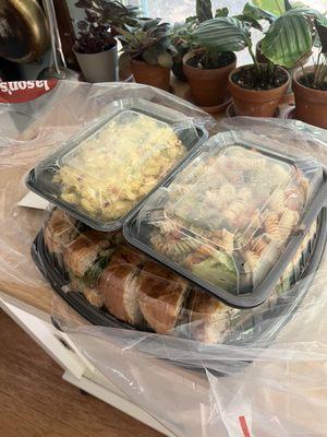 Huge tray of sandwiches with pasta salad and potato salad