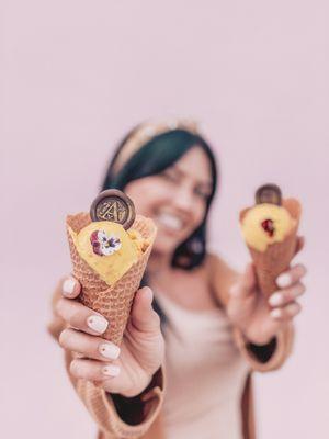 Angie (founder and chef) holds two ice cream cones with our famous flavor: Mango Lassi