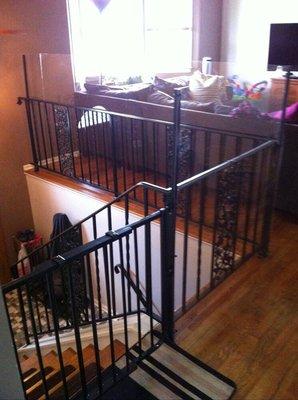 Fitted metal gate matches to black metal stair railings. Gate has one hand release, no tripping hazards, and does not swing into staircase.