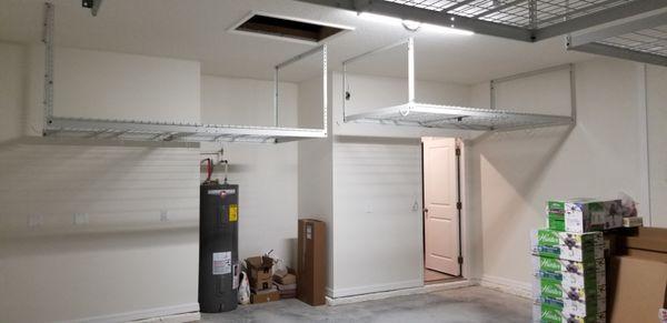 Two overhead garage racks installed across the back wall at different heights and also two more over the garage door.