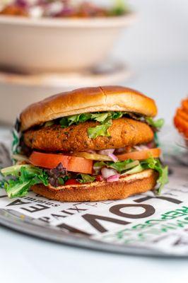 The falafel burger features a chickpea patty with fresh toppings and tahini in a soft bun, offering a flavorful plant-based option.