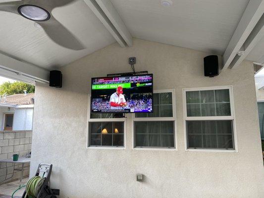 Samsung Signature 4K outdoor TV mounted with Mantel Mount MM700 and Klipsch enviromental speakers in the patio for outdoor entertainment.