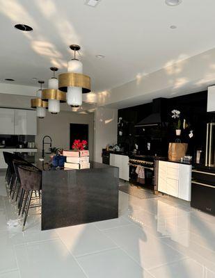 Full wall backsplash, countertops, and a waterfall edge in sleek black granite takes this client's kitchen to the next level!