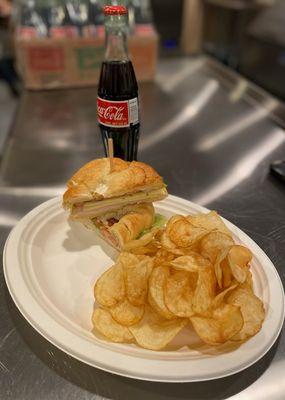 croissant sandwich, chips, and soda.