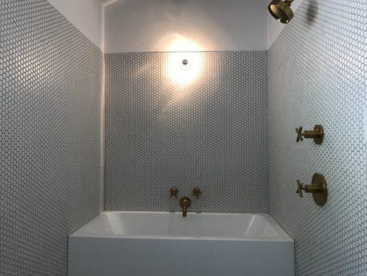 Shower with a bathtub. Penny tile was installed on walls and on floors.