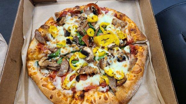 Pizza with pepperoni, sausage, spinach, banana peppers, and mushrooms.