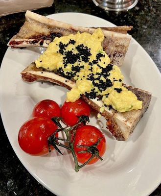 Roasted bone marrow topped with soft scrambled eggs with crème fraiche and chives. Sprinkle of black caviar and a side of roasted tomatoes.