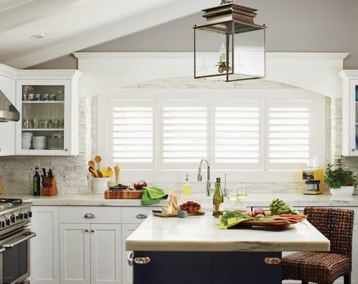 White interior plantation shutters create a clean environment in this traditional white kitchen.