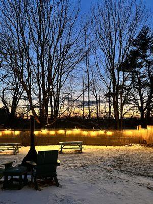 Back yard with large fire pits, tables, and a beautiful sunset